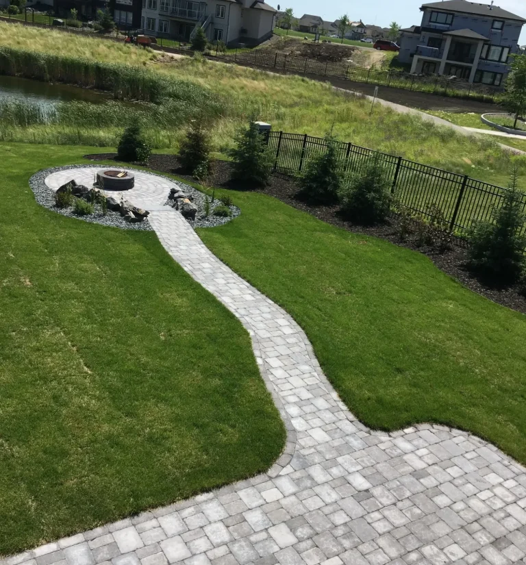 Barkman Roman paver sidewalk leading to sunken circle firepit area surrounded by fresh Kentucky Blue sod completed by Genesis Interlocking & Custom Landscaping